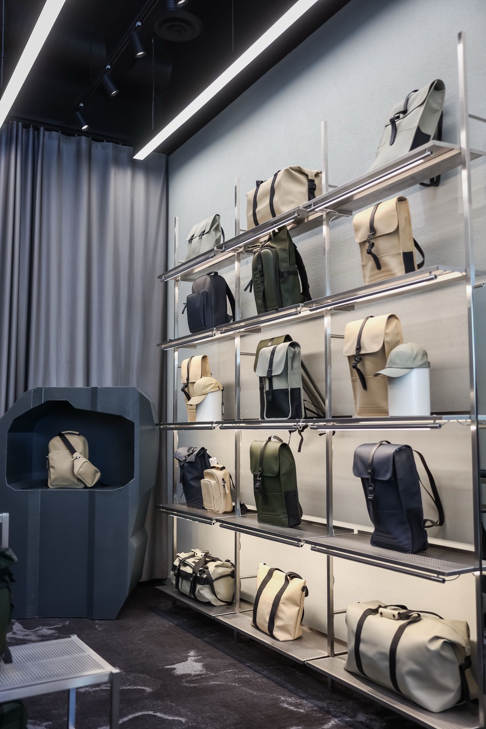 RAINS interior — bag wall with sculptural display plinth, built and merchandised by Readymade